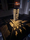 A rustic metal decorative lantern with a cutout American flag pattern and 'USA' embossed on the front.